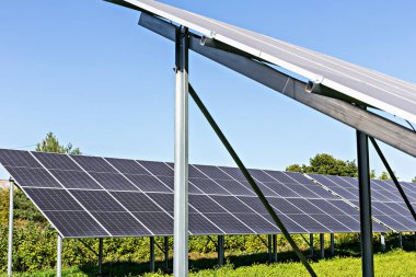 Güneş enerjisi. Yeşil alanda güneş ışığını yakalayan güneş panelleri, yenilenebilir enerji kaynaklarının önemini ve teknoloji ve çevre koruma alanlarındaki sürdürülebilir uygulamaların önemini vurguluyor