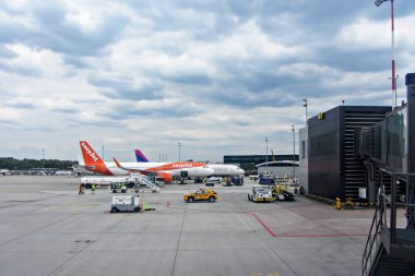 Ivan Paul Havaalanı, Krakow, Polonya - 07 Mayıs 2025: Pistte birden fazla uçak, yer ekibi ve dramatik bulutların bulunduğu yoğun havaalanı sahnesi