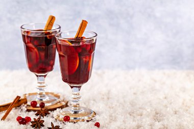Sıcak şarap. Tarçın çubukları ve baharatlarla süslenmiş zarif bardaklarda servis edilen bayram içecekleri yumuşak karlı yüzeyde, kış kutlamaları için sıcak ve davetkar bir ortam yaratıyor.