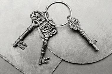 Tabaklarda üç eski anahtar var. Gri arkaplandaki nesneler. Kavramsal fotoğraf. 2026 yılının gösterişli rengi, Bulut, Dansçı