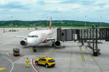 Ivan Paul II Havalimanı, Krakow, Polonya - 07 Mayıs 2025: Havalimanı kapısında yer mürettebatı kalkış, havacılık operasyonları ve yoğun terminal ortamında seyahat lojistiği hazırlıkları yapan uçak