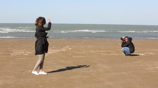 Чоловік фотографує красиву жінку на пляжі . — стокове відео