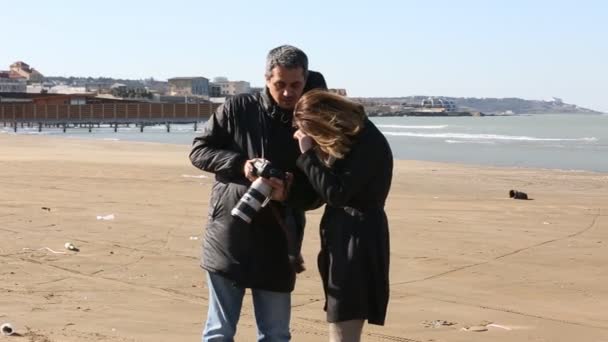 Чоловік фотографує красиву жінку на пляжі . — стокове відео
