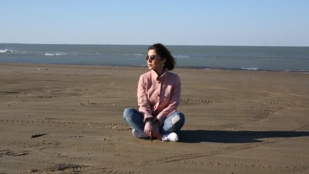 Donna sola seduta sulla spiaggia durante la tempesta di vento. Ragazza siede su dune in fondo deserto spargendo sabbia. tempesta di sabbia — Video Stock