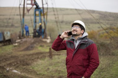 Üniforma ve kask, cep telefonu ile petrol işçisi. 