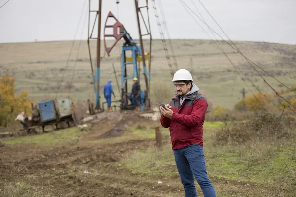 Üniforma ve kask, cep telefonu ile petrol işçisi. 