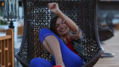 Bir hasır salıncak aqua park üzerinde oturan bir bayan. Kadın parkta güneşli yaz günü askıya bir hasır sandalye sürme gözlük.