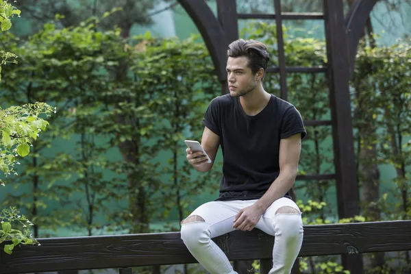 Attraktives junges männliches Model beim Spielen auf einem Smartphone Stockbild