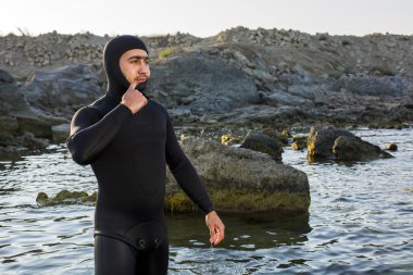 Onun wetsuit üzerinde sahilde koyarak bir genç sörfçü. Adam bir takım elbise sualtı avcısı.