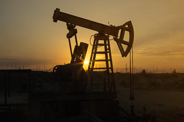 Fossile Brennstoffe Energie, Ölpumpe, Pumpenheber, alte Pumpeneinheit, Wagenheberpumpe, Sonnenuntergang. Reihen von Öl-Esel in der Silhouette bei Sonnenuntergang Rohöl. — Stockfoto