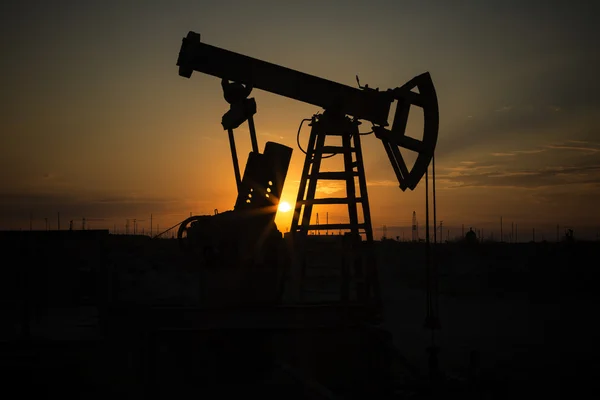 Energía de combustible fósil, bomba de aceite, bombeo, unidad de bombeo antigua, bomba Jack, puesta del sol.Filas de burro de aceite en silueta al atardecer petróleo crudo . — Foto de Stock