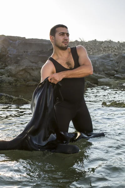 Onun wetsuit üzerinde sahilde koyarak bir genç sörfçü. Adam bir takım elbise sualtı avcısı.