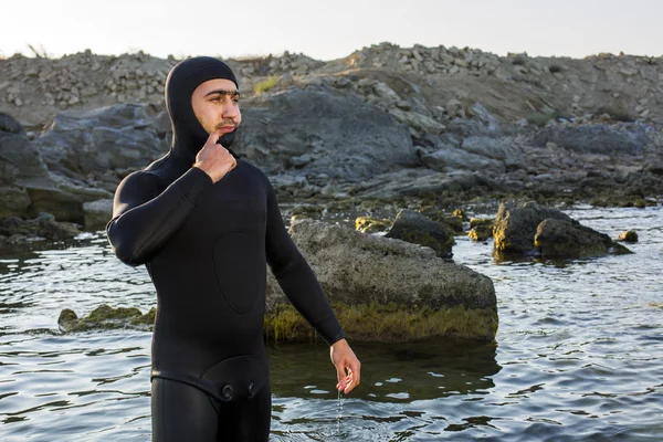 Onun wetsuit üzerinde sahilde koyarak bir genç sörfçü. Adam bir takım elbise sualtı avcısı.