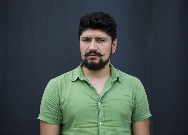 Yeşil gömlekli serin bıyıklı adam sakallı. çok sinirli bir adam