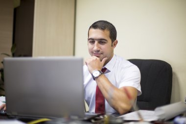 ofiste dizüstü bilgisayar üzerinde çalışan genç adam