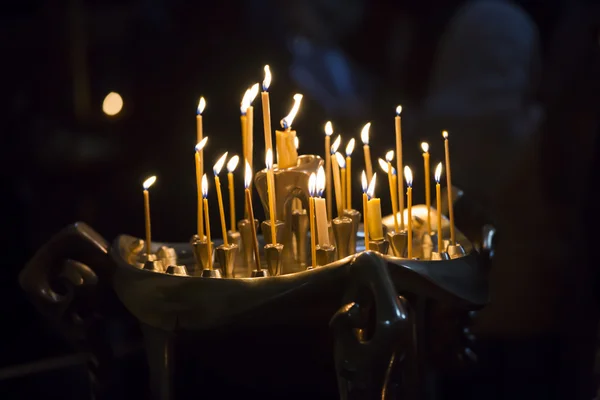 Lumânările din Biserica Georgiană. Lumânări lungi luminate grup pe fundal negru . — Fotografie, imagine de stoc