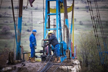 Petrol İşçileri petrol pompa kontrol edin. Roustabouts bir petrol kuyusu sondaj platformu hizmet işi pis ve tehlikeli. Kasım 2015 Şabran, Azerbaycan