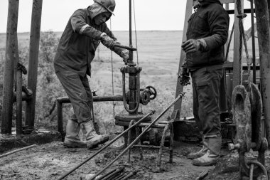 Petrol İşçileri petrol pompa kontrol edin. Roustabouts bir petrol kuyusu sondaj platformu hizmet işi pis ve tehlikeli. Kasım 2015 Şabran, Azerbaycan