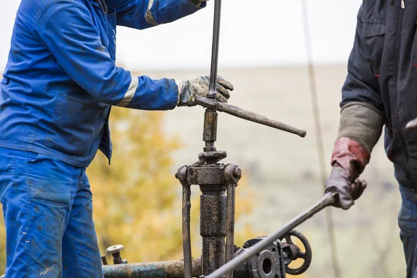 Olie werknemers controleren oliepomp. Roustabouts vuile en gevaarlijke werk op een olie goed onderhoud tuig. — Stockfoto