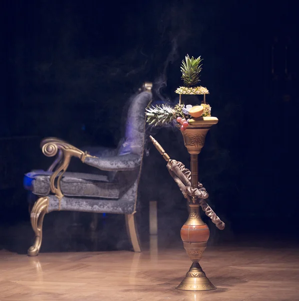 Um narguilé exótico. Gancho diferente sobre os fundos brilhantes com fumaça. Hookah com sabor a frutas na mesa de madeira em estilo vintage — Fotografia de Stock