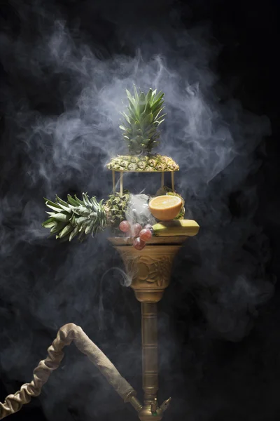 Um narguilé exótico. Gancho diferente sobre os fundos brilhantes com fumaça. Hookah com sabor a frutas na mesa de madeira em estilo vintage — Fotografia de Stock