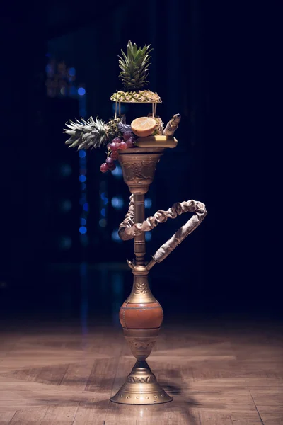 Um narguilé exótico. Gancho diferente sobre os fundos brilhantes com fumaça. Hookah com sabor a frutas na mesa de madeira em estilo vintage — Fotografia de Stock