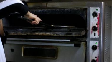 Şef baker mutfak Pizza'da yapma beyaz üniformalı closeup el. Geleneksel ahşap yanan bir restoranda pizza-ekmek fırınında pişmiş pizza. Ticari mutfakta pizza yapma Şef. Pizzacı