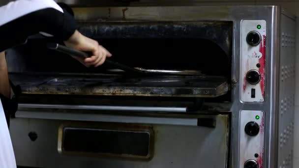 Primeros planos de cocinero panadero en uniforme blanco haciendo pizza en la cocina. Pizza que se hornea en el horno tradicional de leña de pan de pizza en un restaurante. Chef haciendo pizza en la cocina comercial.Pizza Place — Vídeo de stock