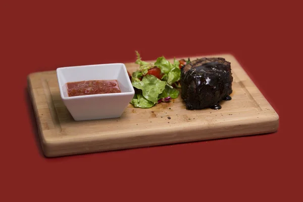 나무 테이블에 맛 있는 쇠고기 스테이크 클로즈업. 커팅 보드에 야채와 구운된 송아지 고기 스테이크. — 스톡 사진