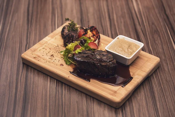 Delicious beef steak on wooden table, close-up. Grilled veal steaks with vegetables on cutting board. — Stock Photo, Image