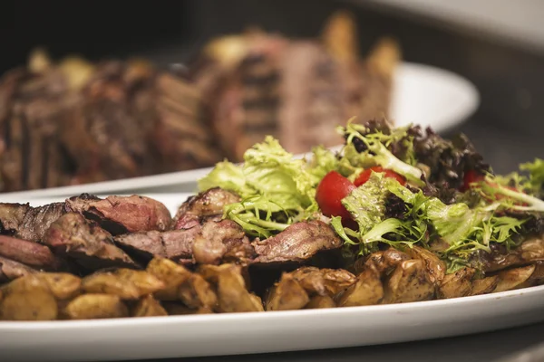 Köstliches Rindersteak auf Holztisch, aus nächster Nähe. Kalbssteaks vom Grill mit Gemüse auf Schneidebrett. — Stockfoto