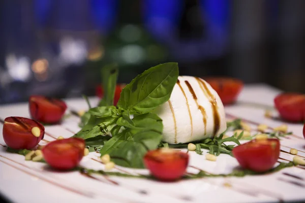 Weiße Schüssel mit frischem und gesundem mediterranem Salat mit Mozzarella, Tomaten und Basilikumblättern. Caprese: Kirschtomaten, Mozzarella-Bällchen und Basilikumblätter. — Stockfoto