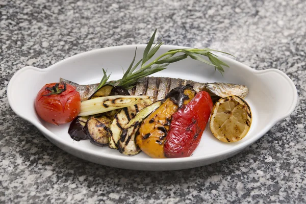 야채와 함께 구운된 생선입니다. 나무 테이블에 접시에 생선을 훈제 — 스톡 사진