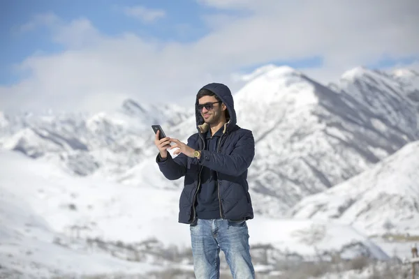 bir kış günü açık havada üzerinde yürüyen bir genç adam. Genç adam selfie kara kış gününde zevk alarak.