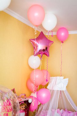 Odanın köşesindeki bebek yatağı balonlarla süslenmiş..
