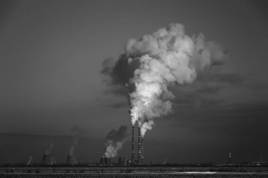 Kalın duman endüstriyel borulardan yükseliyor. Çevrenin atık ürünlerle kirlenmesi. Siyah beyaz fotoğraf.