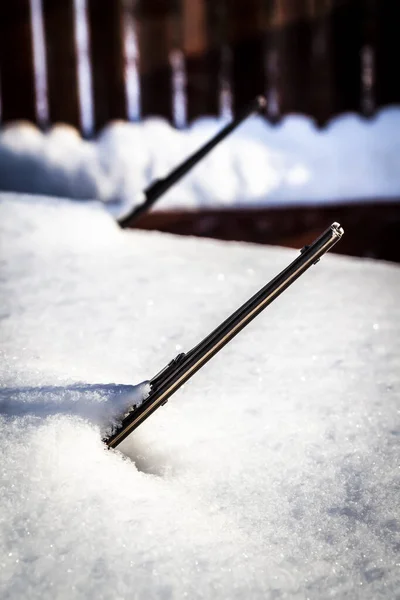 The raised wiper blade sticks out from under the snow.