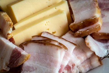 Yakın plan bir tabakta dilimlenmiş jambon ve peynir..