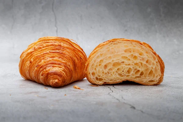 Çimento arka planındaki kıvrımlara göre dilimlenmiş kruvasanda bal peteği..