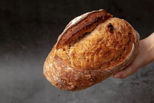 Sourdough bread with mixed fruits and nuts on dark cement background.