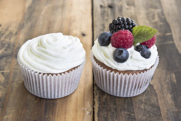 Deux cupcakes différents sur une table en bois rustique — Photo