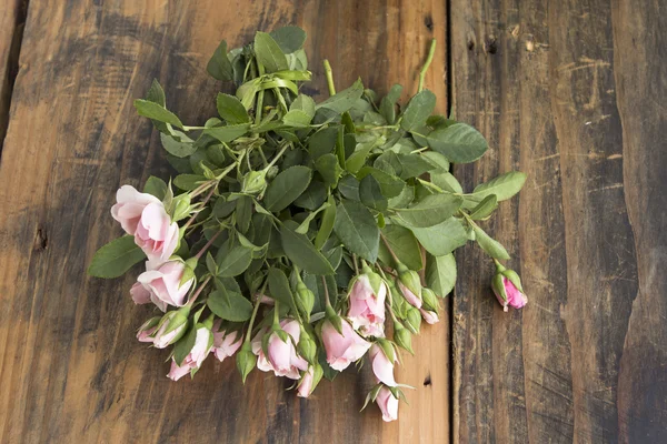 Bouquet di rose rosa germogli su uno sfondo rustico di una tavola — Foto Stock