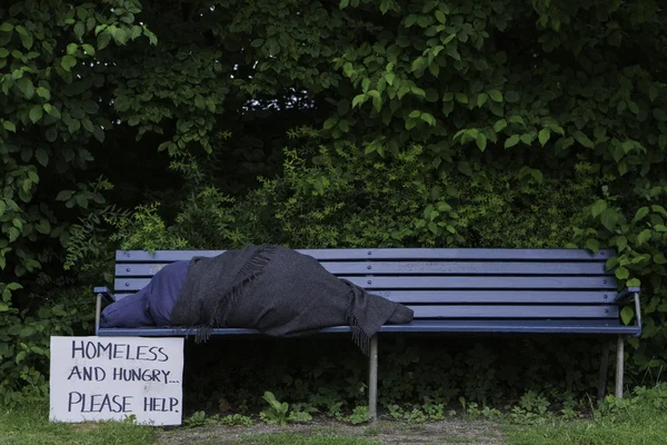Bezdomovec na lavičce v parku — Stock fotografie
