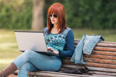 Dizüstü bilgisayar kullanan kızıl saçlı kadın.