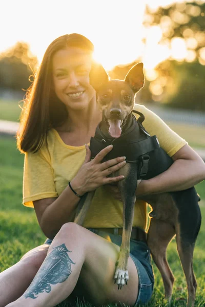 Vacker kvinna sitter och håller sin hund i parken — Stockfoto