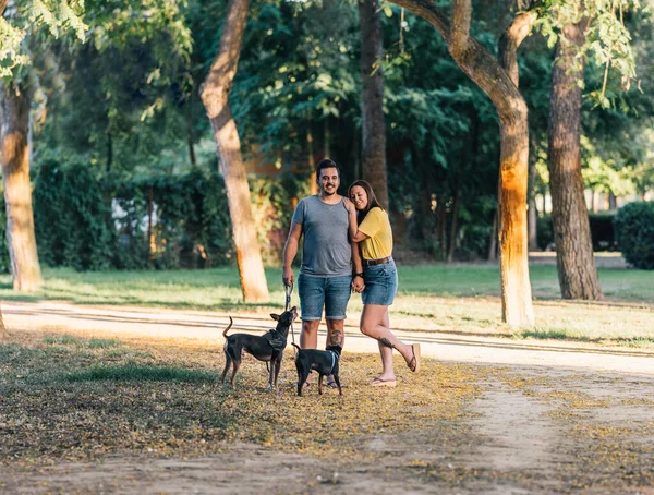 Par poserar med sina två hundar i en park — Stockfoto