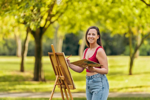 Mulher em roupas de verão pintura em uma tela ao ar livre — Fotografia de Stock