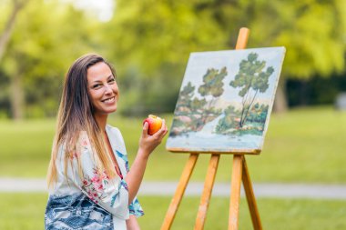 Ressam parkta elma yiyor.