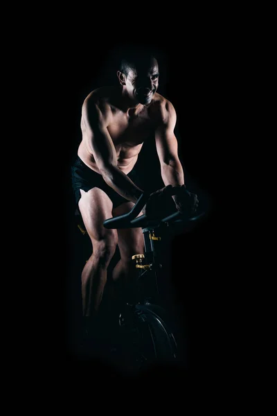 Homem forte usando a bicicleta estática. — Fotografia de Stock