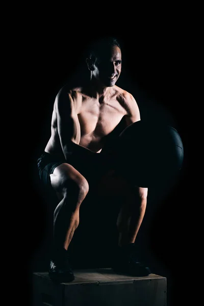 Homem forte fazendo agachamentos com uma bola medicinal i — Fotografia de Stock